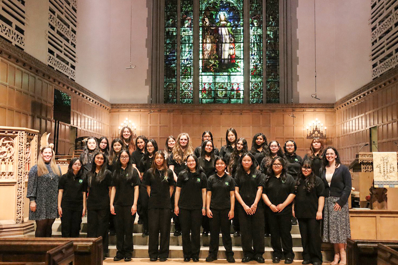 Group photo of the SJMP choir in Timothy Eaton Memorial Church with audience members in the pew