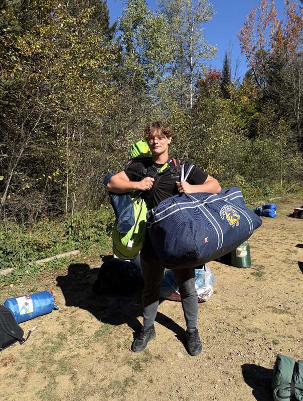 Photo of a Chaminade student on the excursion holding large bags with camping gear
