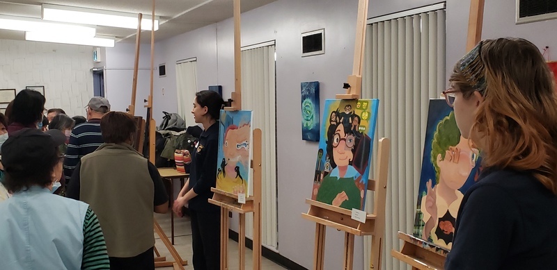 Students showcase art exhibits at Piece Out presentation while members of the school community look at the art Students showcase art exhibits at Piece Out presentation while members of the school community look at the art