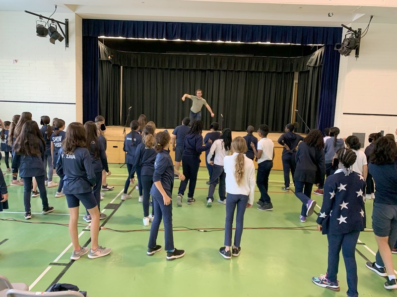 Group of students dancing together under the coaching of a dancing professional on stage