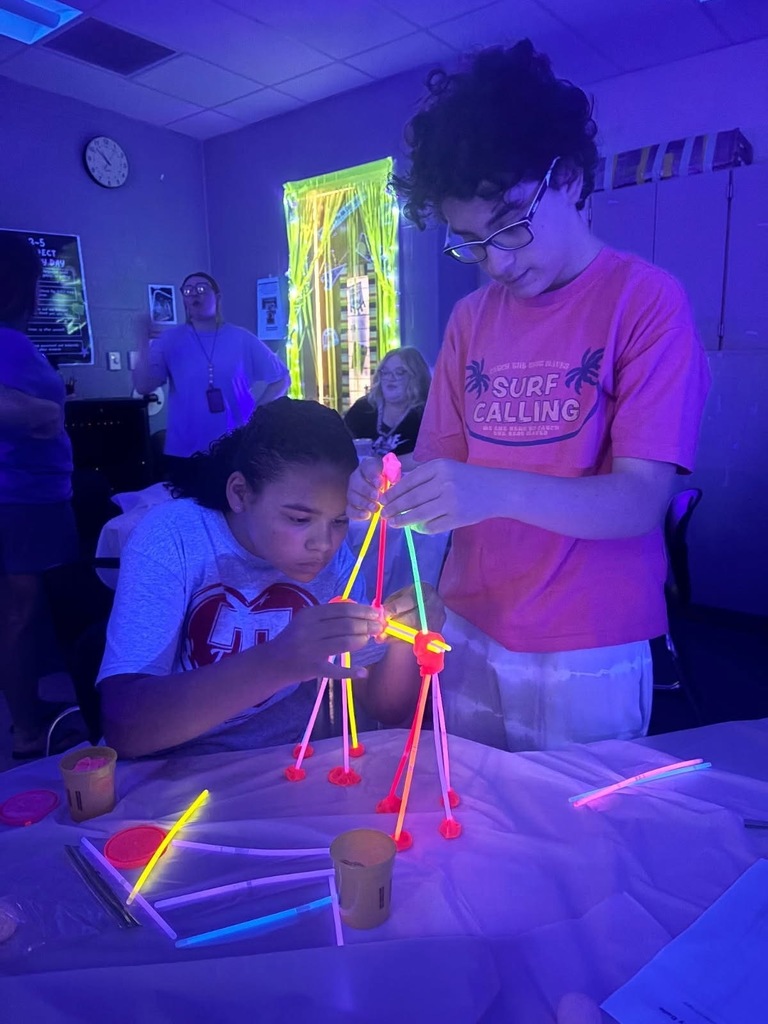 Two students building a structure with glow-in-the-dark materials. 
