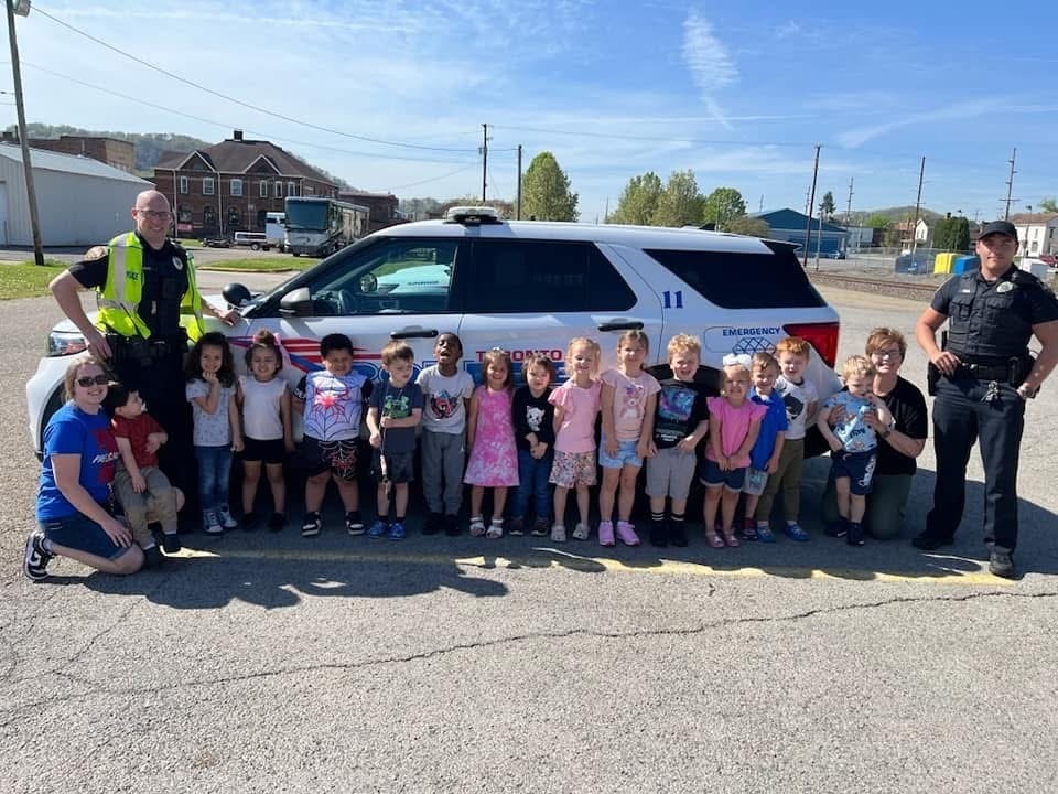 Students gathered around a police car with two police officers.
