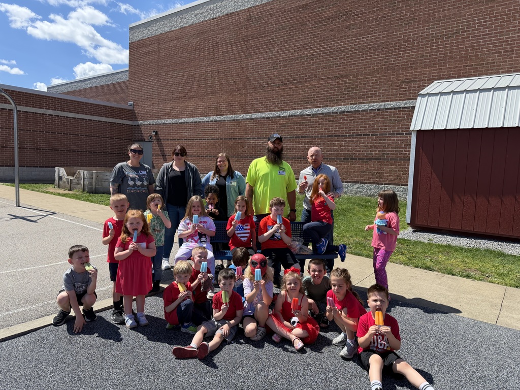 Students and parents outside with popsicles on the playground.