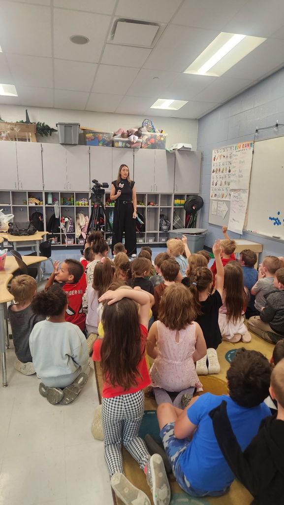Students with guest career speaker. Speaker has a camera from the news.