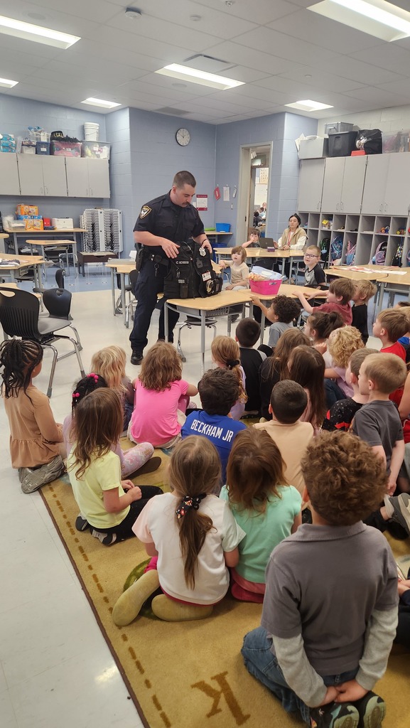 Students with guest career speaker. Speaker is a police man showing his gear.