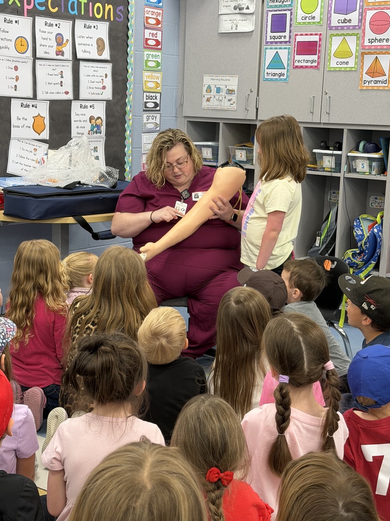 Students with guest career speaker. Demonstrating taking blood from arm with IV.