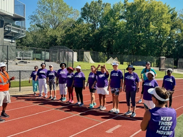 Line of seniors in purple shirts on a track starting line on a sunny day