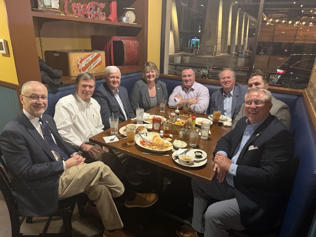 Group of professionals sitting in a booth around a restaurant table.