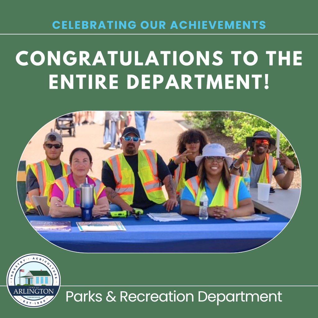Celebrating our Achievements graphic. Light green background with white text saying: Congratulations to the entire department - Parks and Recreation.  Includes a picture in center of 6 employees wearing safety vests seated at a table during an event. 