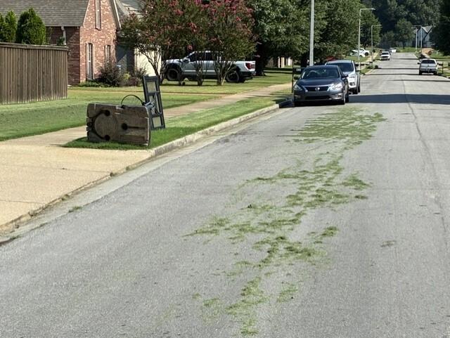 Photo of a 2-lane residential sstreet with grass clippings in the street alongside a freshly mowed yard
