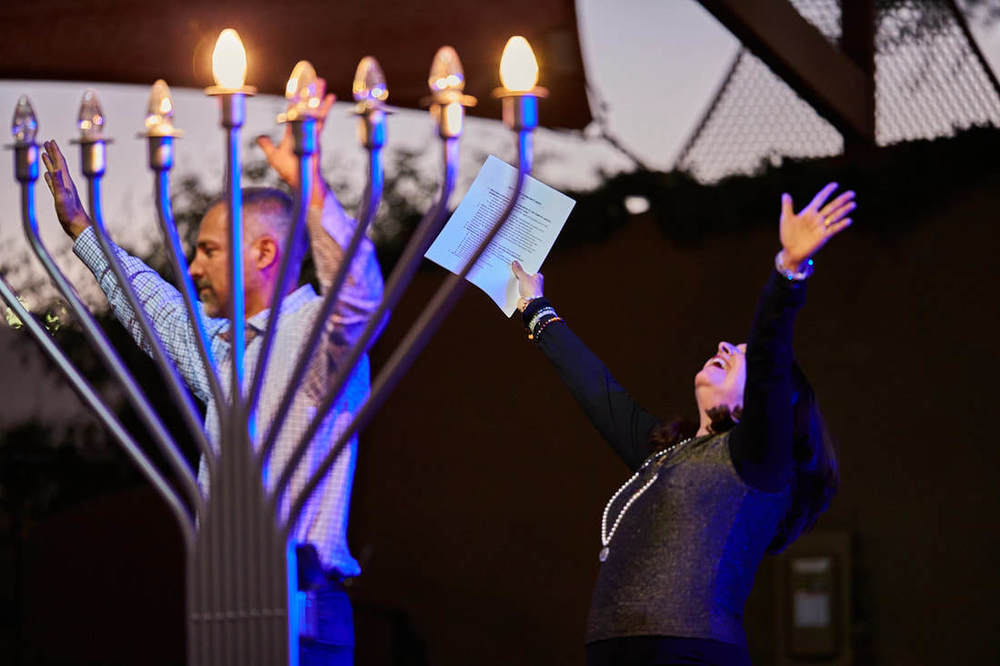 Man and woman praising with menorah