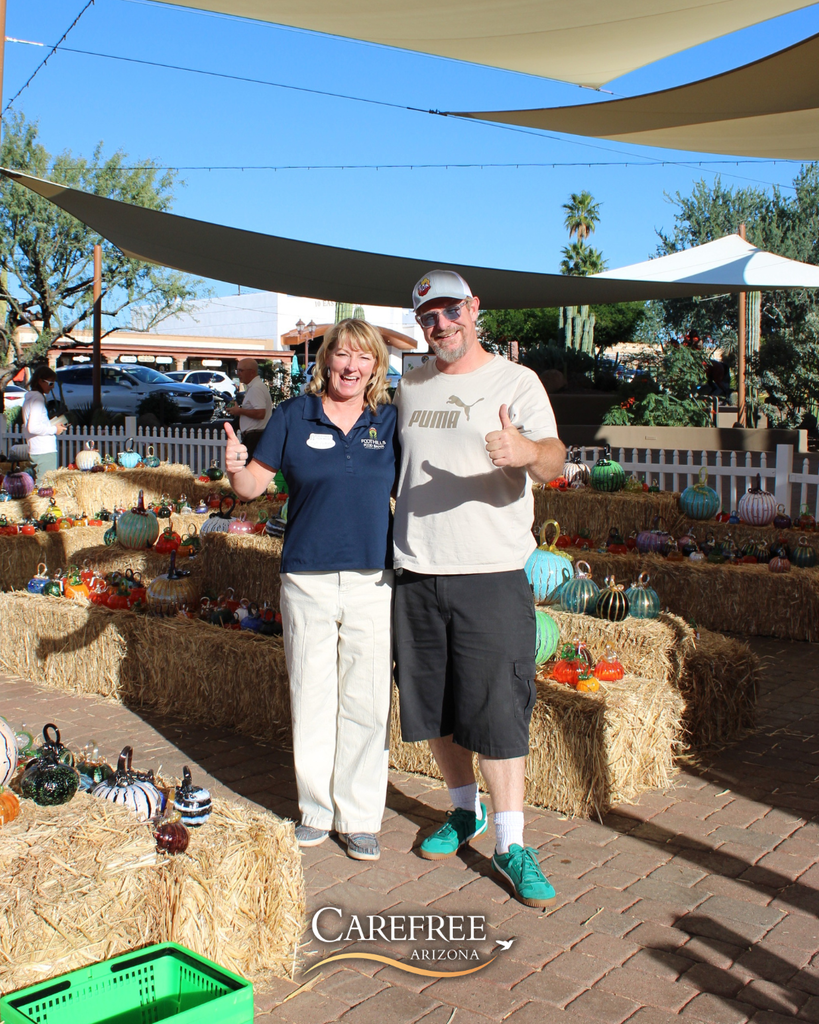 Greg Tomb and Leigh from the Food Bank smiling in front of pumpkins