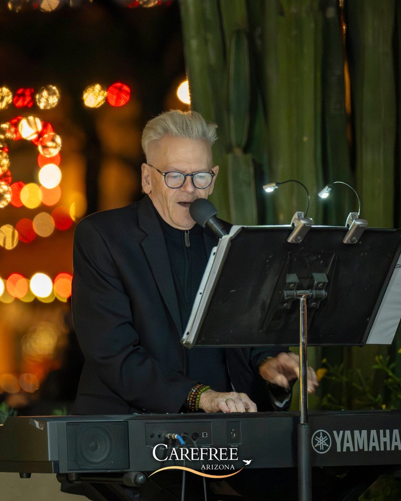 Man singing into microphone at a piano keyboard