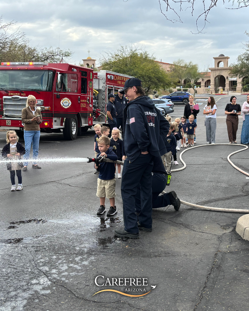 Kid spraying fire hose with firefighters