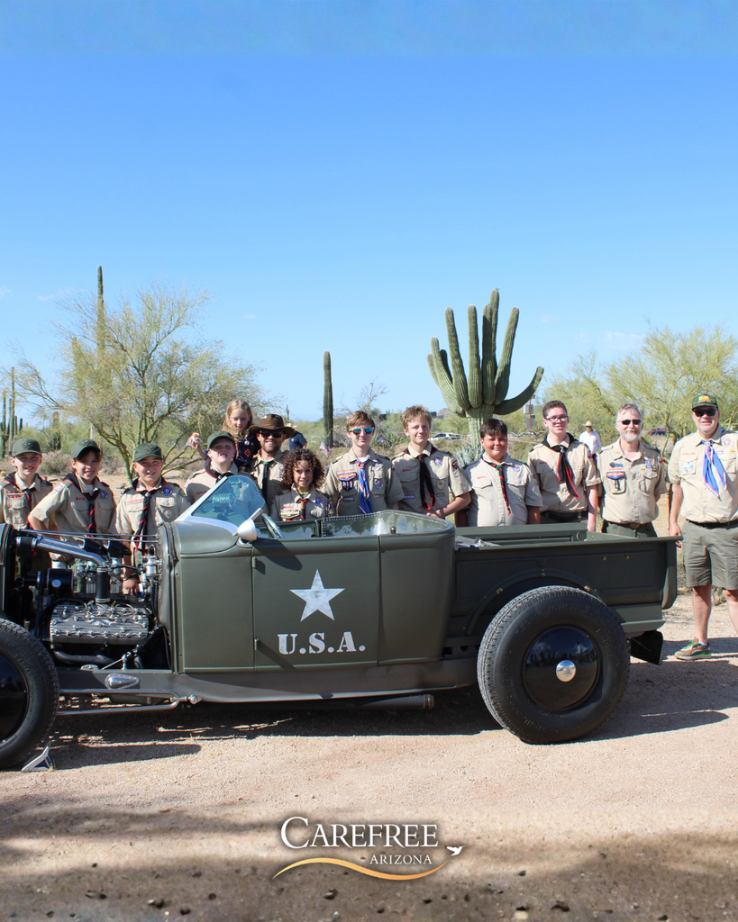Boy scouts posing by army vehicle