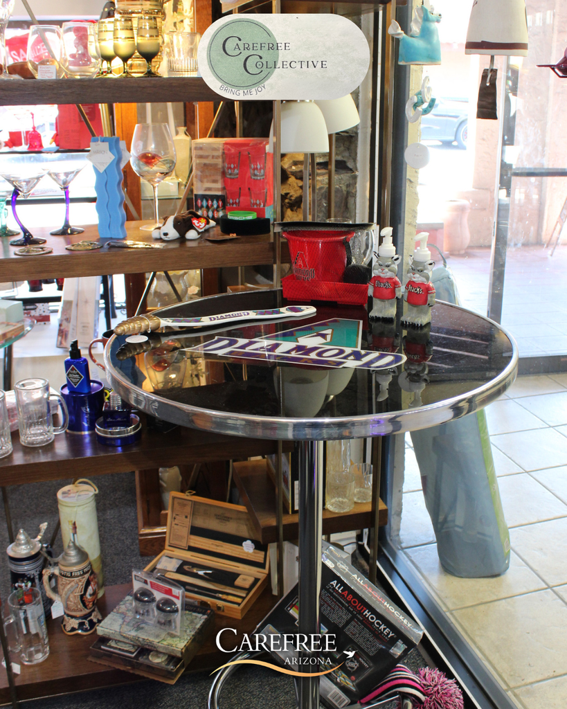 Round glass table with hockey sticks, pucks, and sports memorabilia displayed in a shop window in Carefree, Arizona.