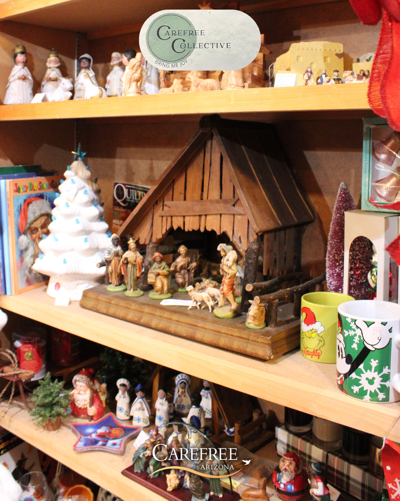 Wooden nativity scene with figurines of Mary, Joseph, baby Jesus, and animals on a shelf surrounded by Christmas decorations.