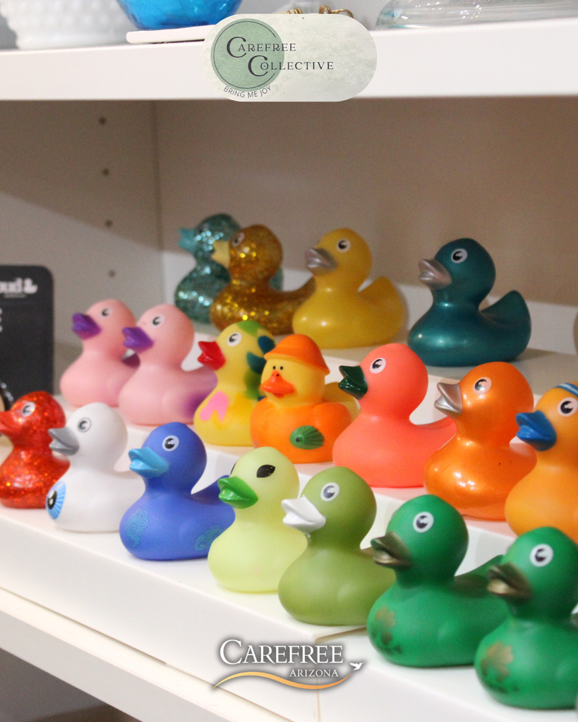A colorful collection of rubber ducks in various shades arranged on white shelves.