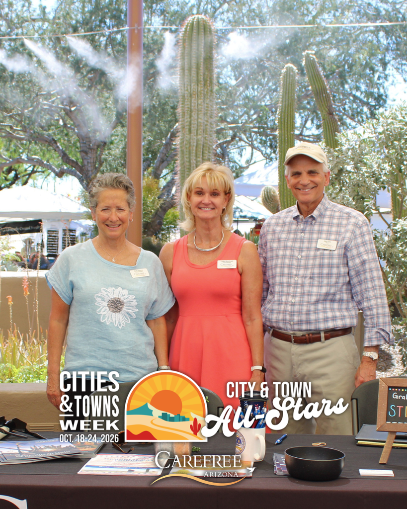 Three Carefree Town Council members smile behind an information table at an outdoor community event.
