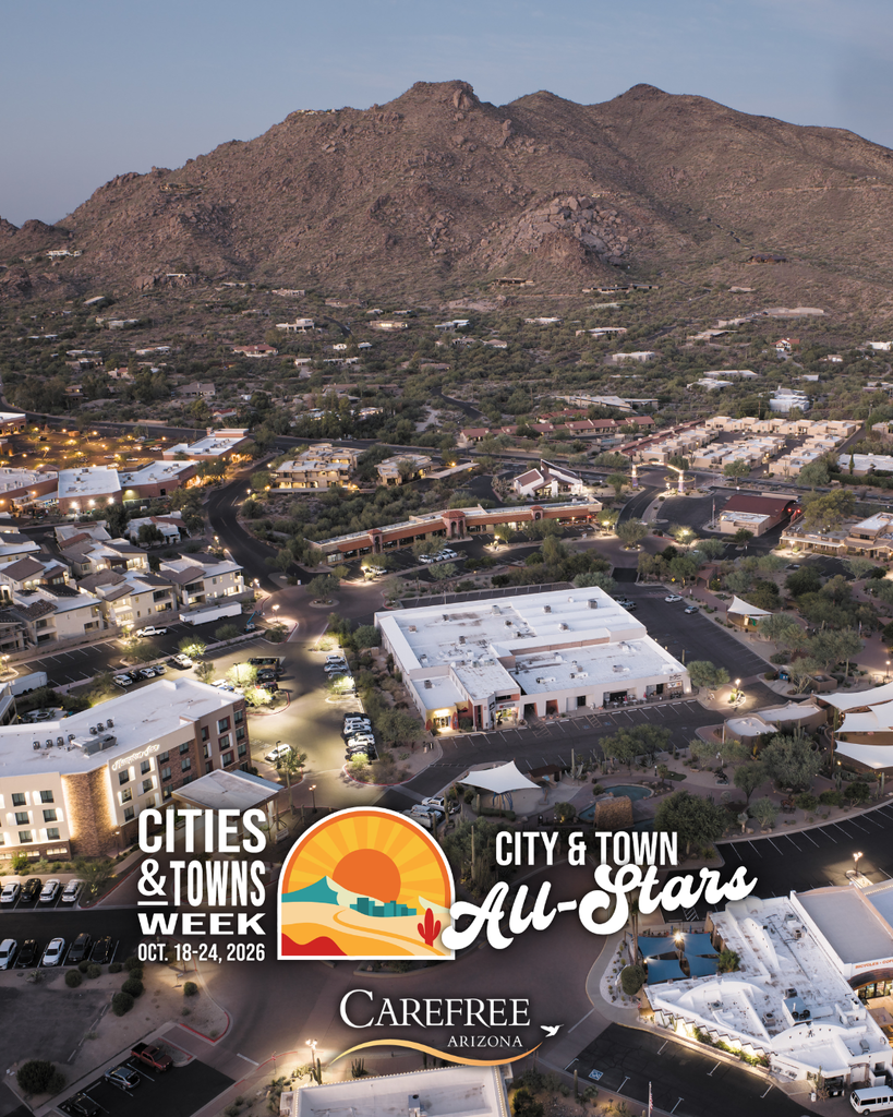 An aerial view of Carefree Town Center at dusk showcases local businesses, buildings, and surrounding desert mountains.