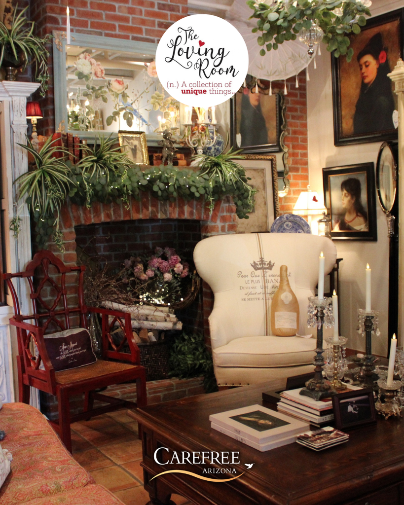 Cozy living room with vintage armchairs, a brick fireplace adorned with greenery, and classic portraits on the walls.