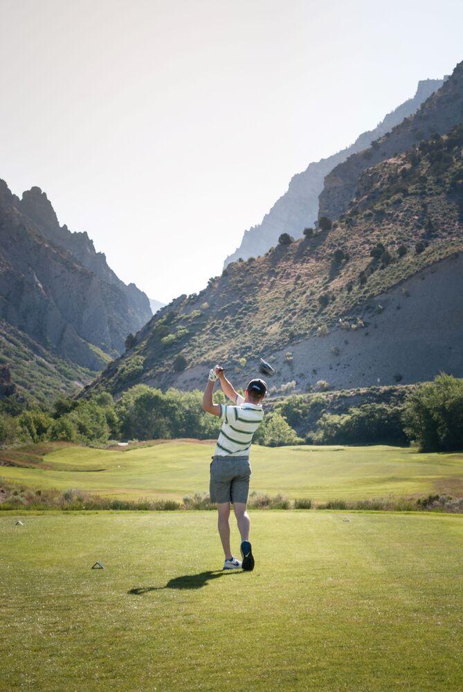 man golfing with mountains in background