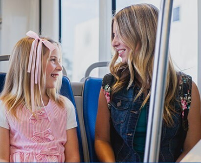 woman and young girl looking at each other and smiling in a public transit vehicle