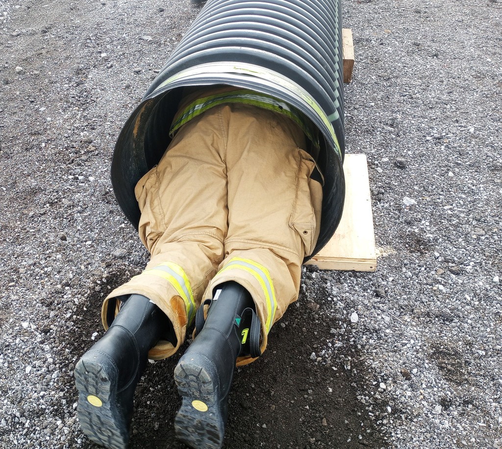 firefighter crawling through pipe