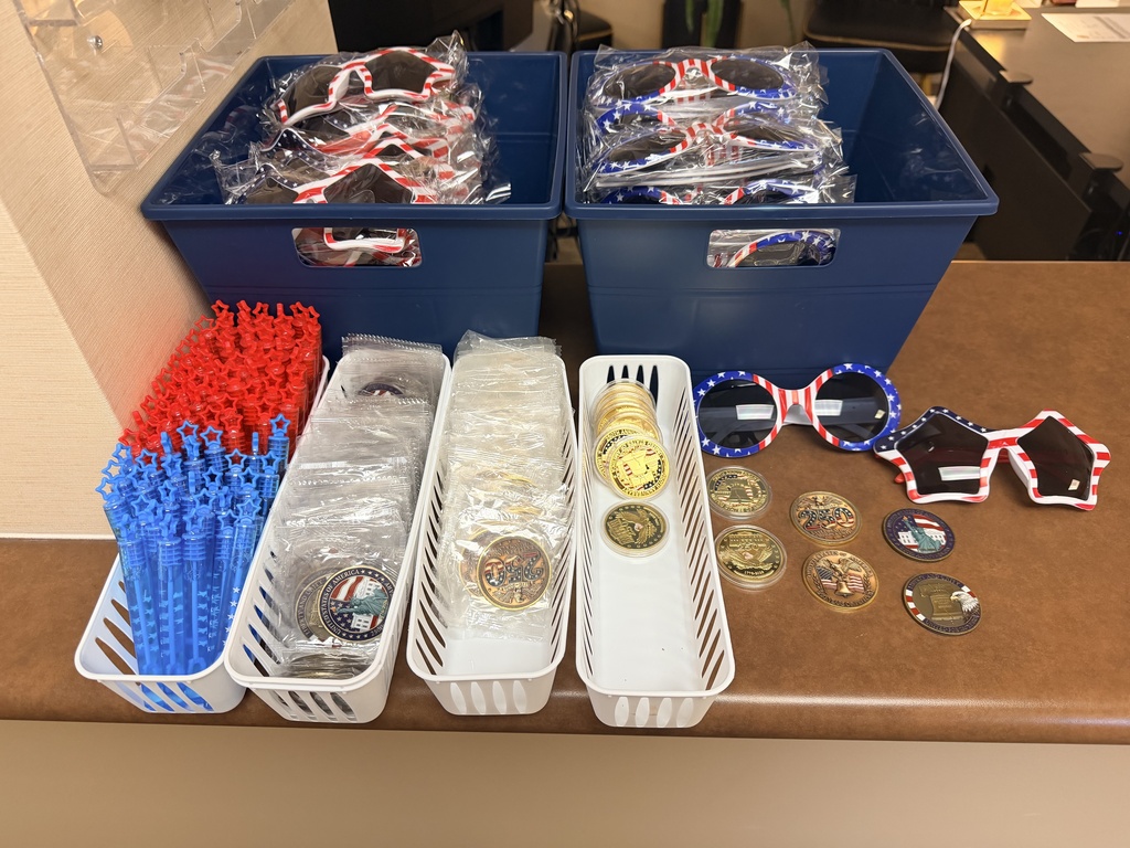 Star Spangled Celebration giveaways includes star shaped American flag glasses, round shaped American flag glasses, commemorative challenge coins celebration America 250 in baskets and laid out on a table.
