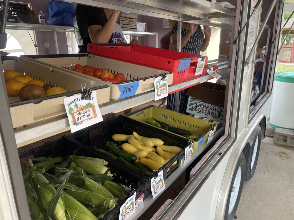 green corn and produce on a shelf with price tags