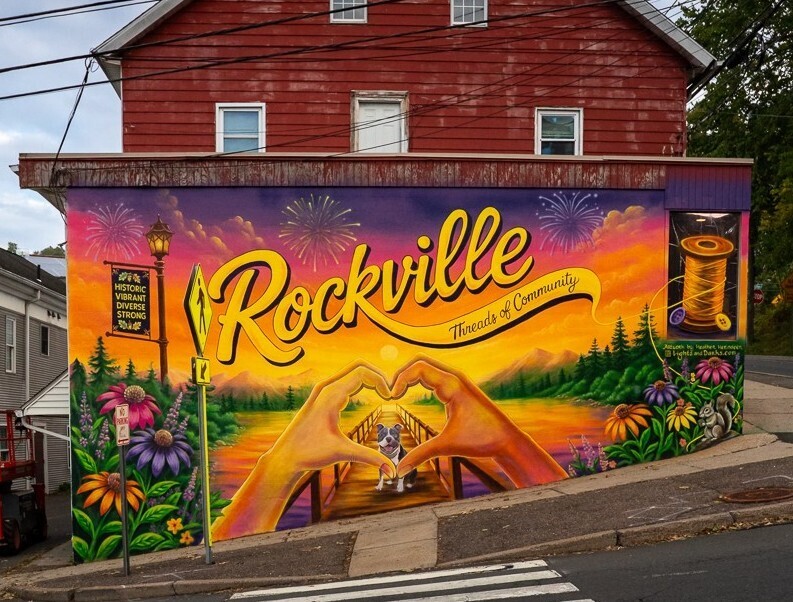 Threads of community mural - colorful mural with Rockville spelled out, hands shaped in a heart, flowers, a dog and a bridge.
