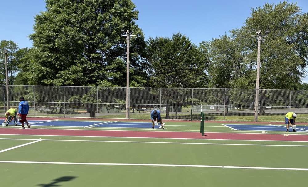 Workers linking tennis and pickleball court at Henry Park