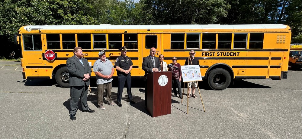 School bus with people standing in front speaking about cameras