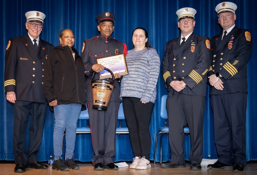 Vernon Firefighter Edgar Jackson, holding the bucket, was honor for 50 years of service. He is standing with his family and fire department leders.