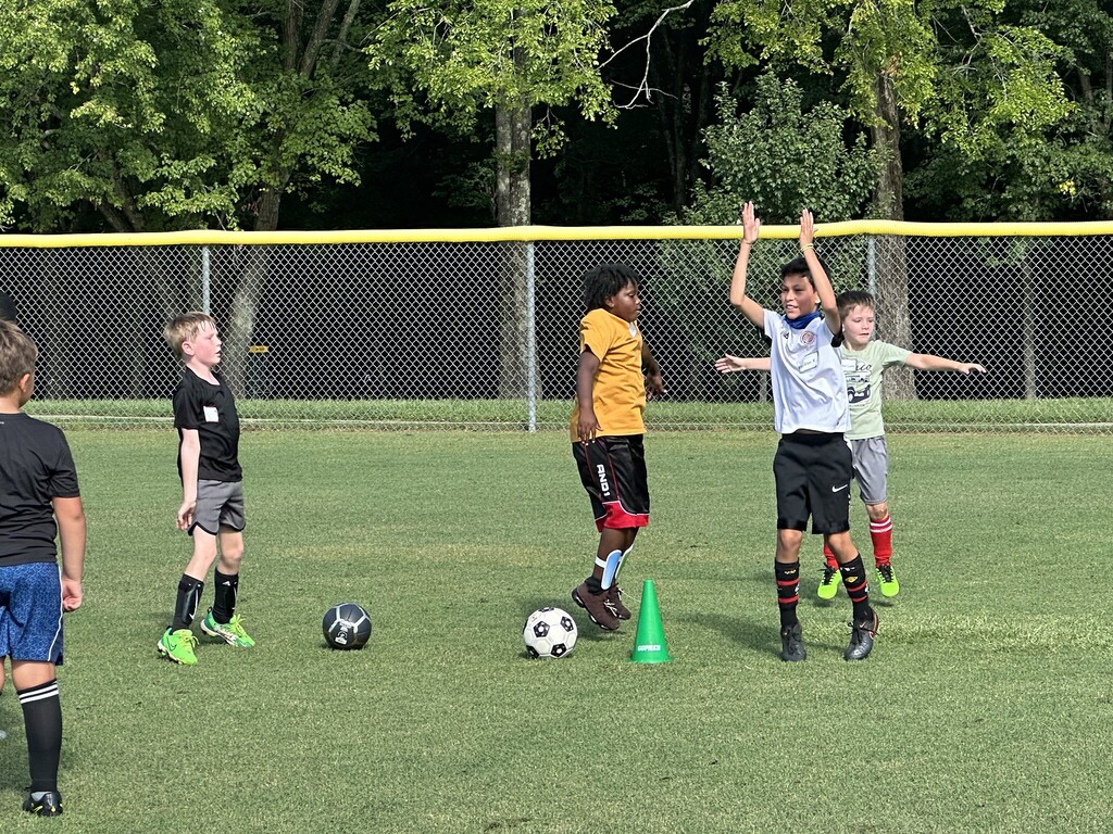 Children playing in the soccer field at soccer camp.
