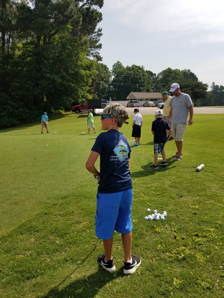 Child standing on golf course at golf camp.