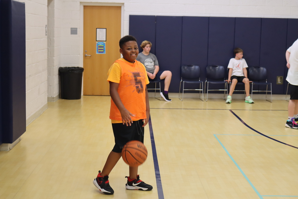 Child smiling and dribbling a basketball.