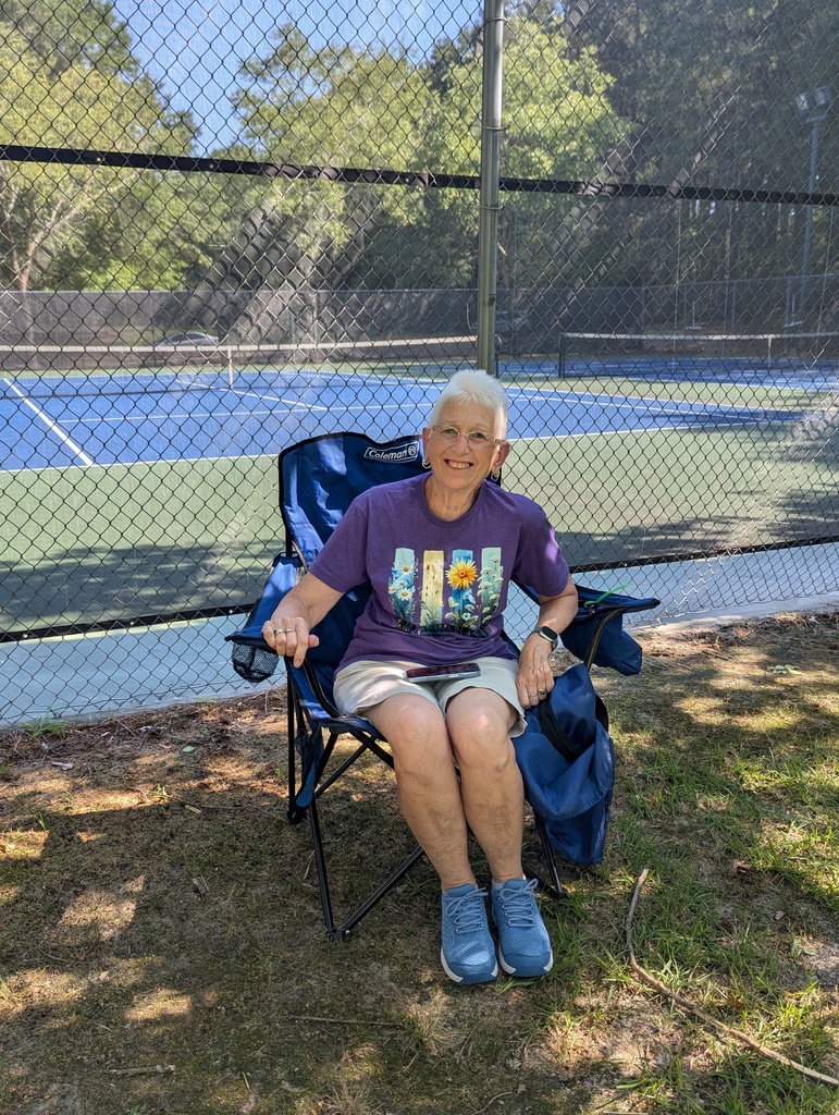 Attendee sitting in lawn chair smiling.