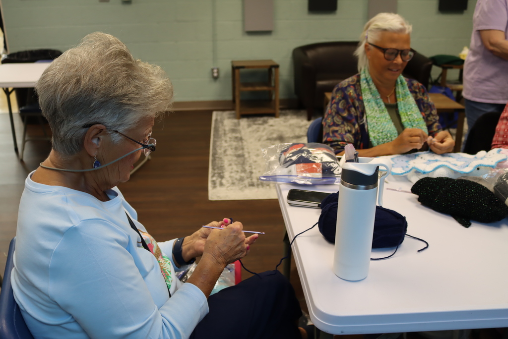 Two women sitting at a table knitting carefully