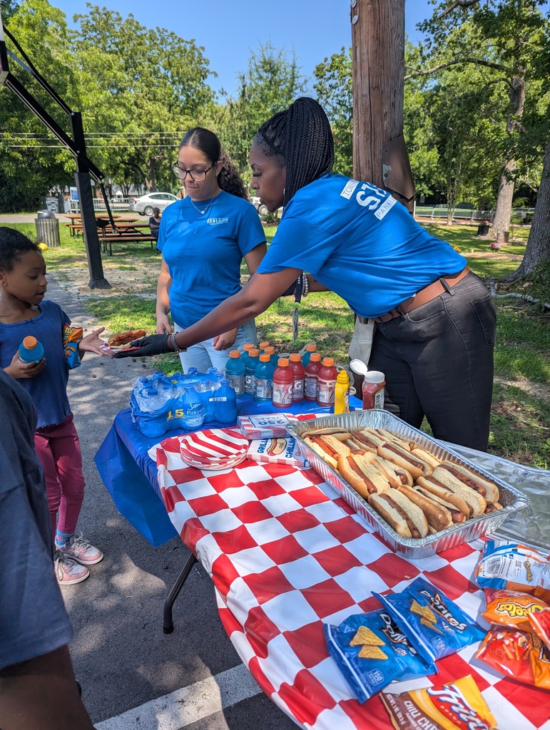Staff serving a hot dog to a child.