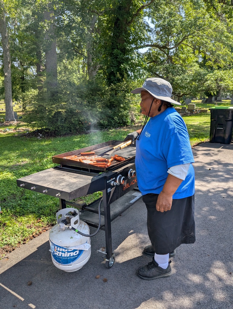 Woman grilling hot dogs outside.