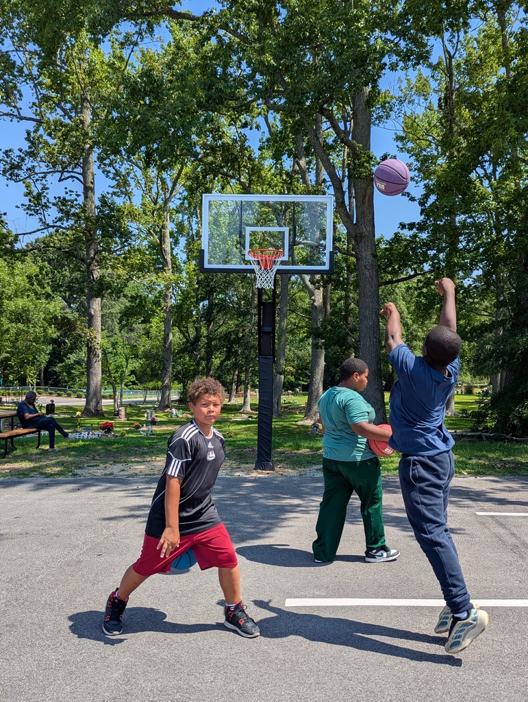 Three boys playing basketball outside.