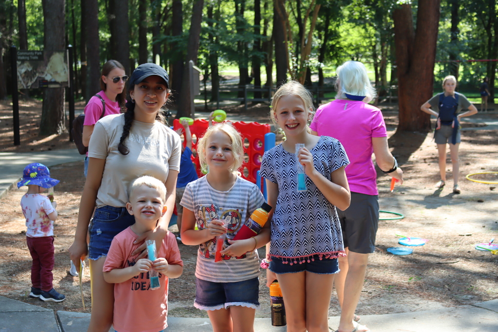 Family smiling at camera while eating popsicles at the park