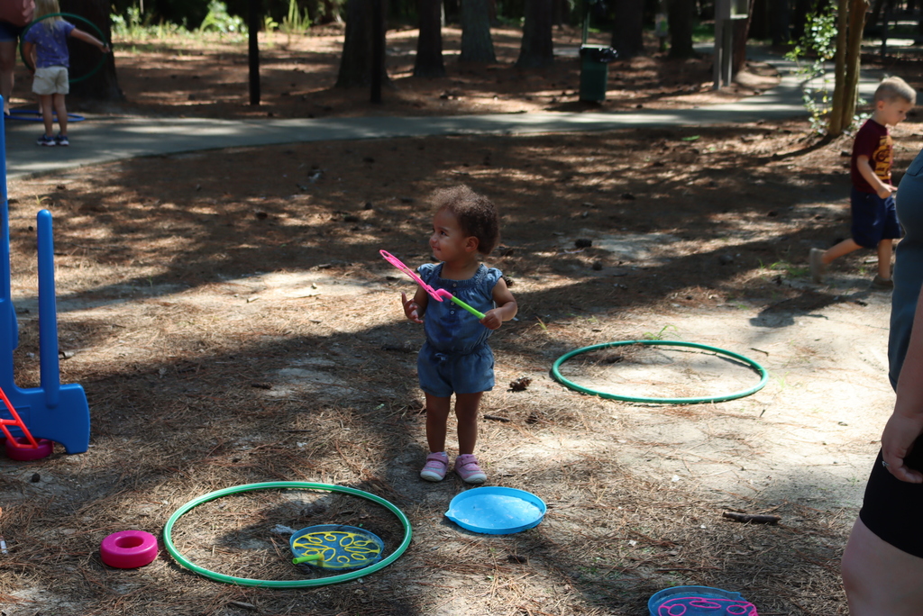 Little girl standing at the park while holding a bubble wand