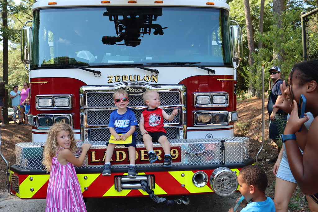 Little boys sitting on the front of a fire truck