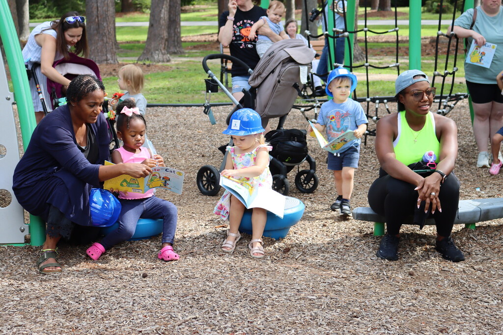 Children reading on the playground equipment while wearing hardhats