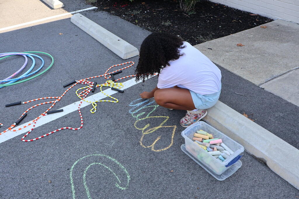 A girl drawing with sidewalk chalk.