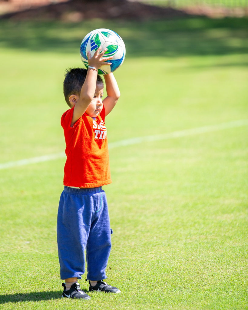 child holding soccer ball above head