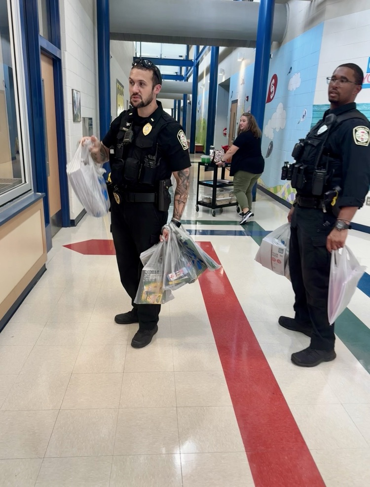 two officers carrying bags of school supplies