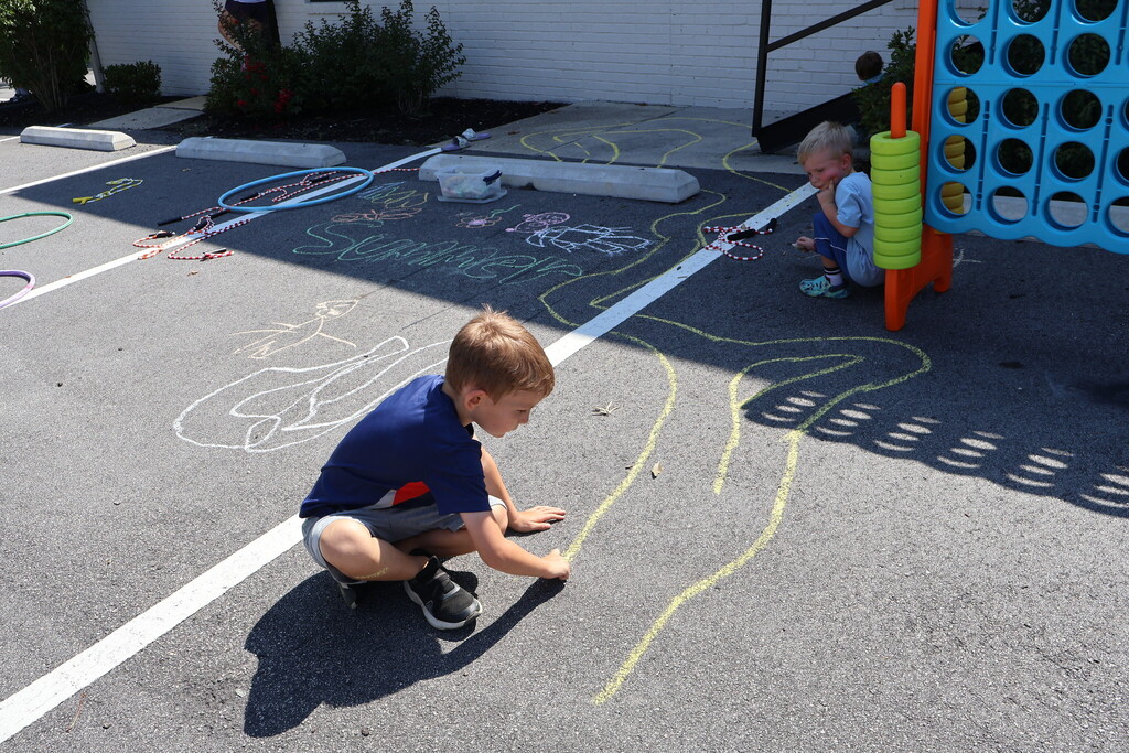 Little boy drawing with sidewalk chalk.